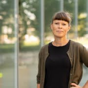 Kvinne foran bygning. Foto.