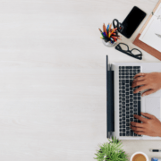 oversiktsbilde over et skrivebord, hender som skriver på et tastatur, objekter på skrivebord. Illustrativt foto.