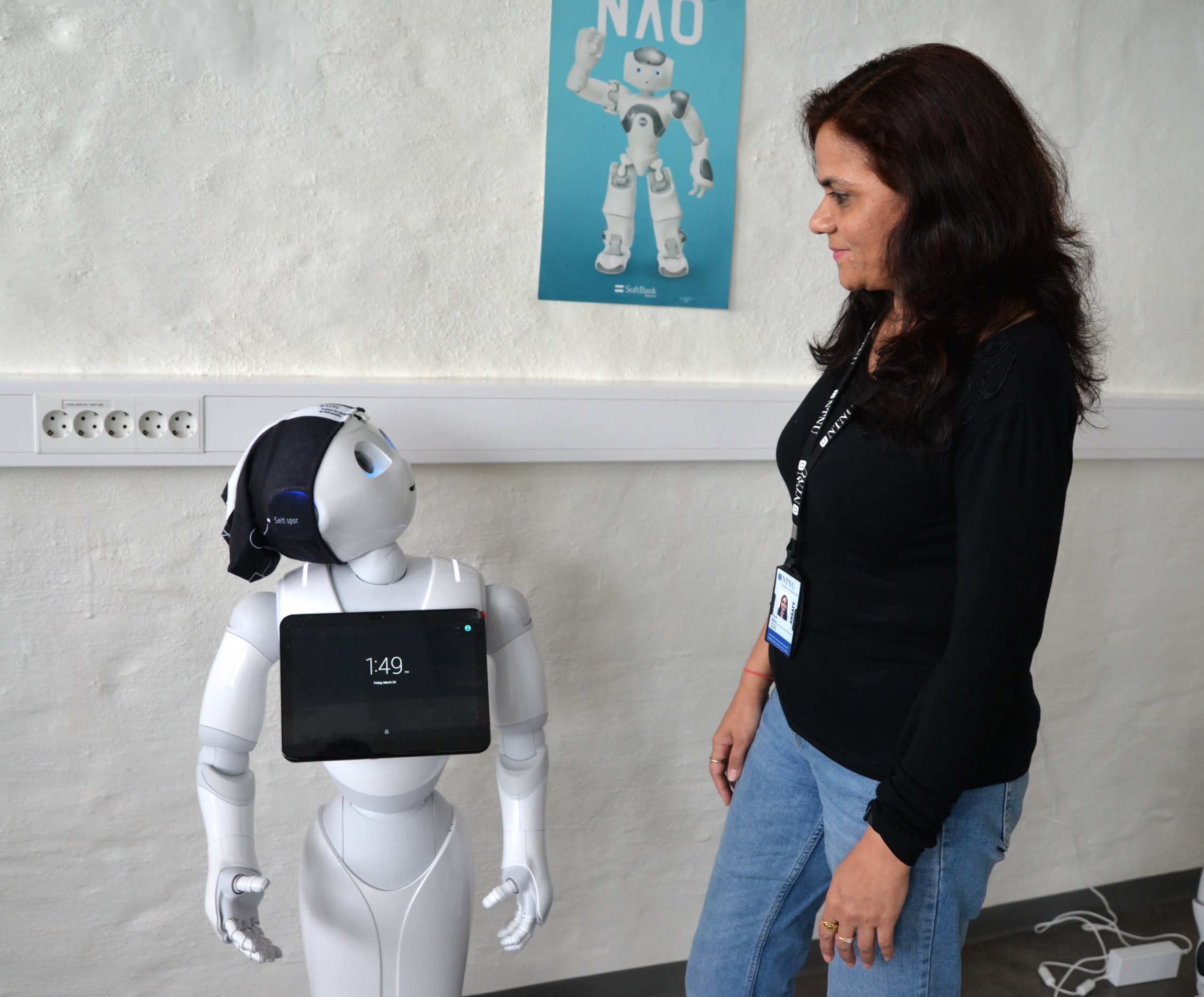 Liten robot sammen med kvinnlig forsker, ser på hverandre. Foto.