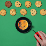 hånd på musepeker som klikker på en kaffekopp og en rekke kjeks som ligger oppstilt på rekke på grønn bakgrunn. illustrasjonsfoto.
