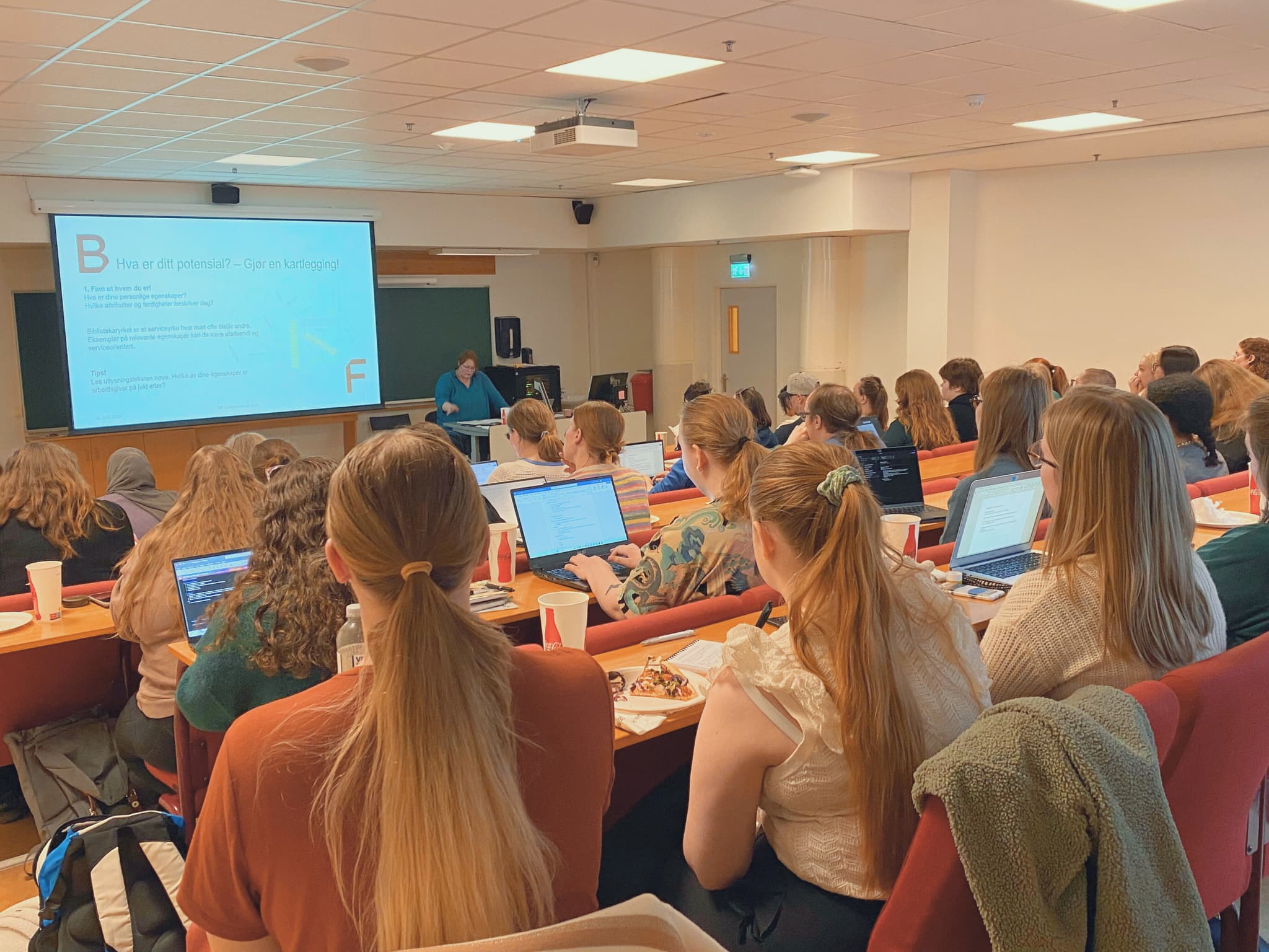 unge mennesker i auditorium følger med på foreleser. foto.