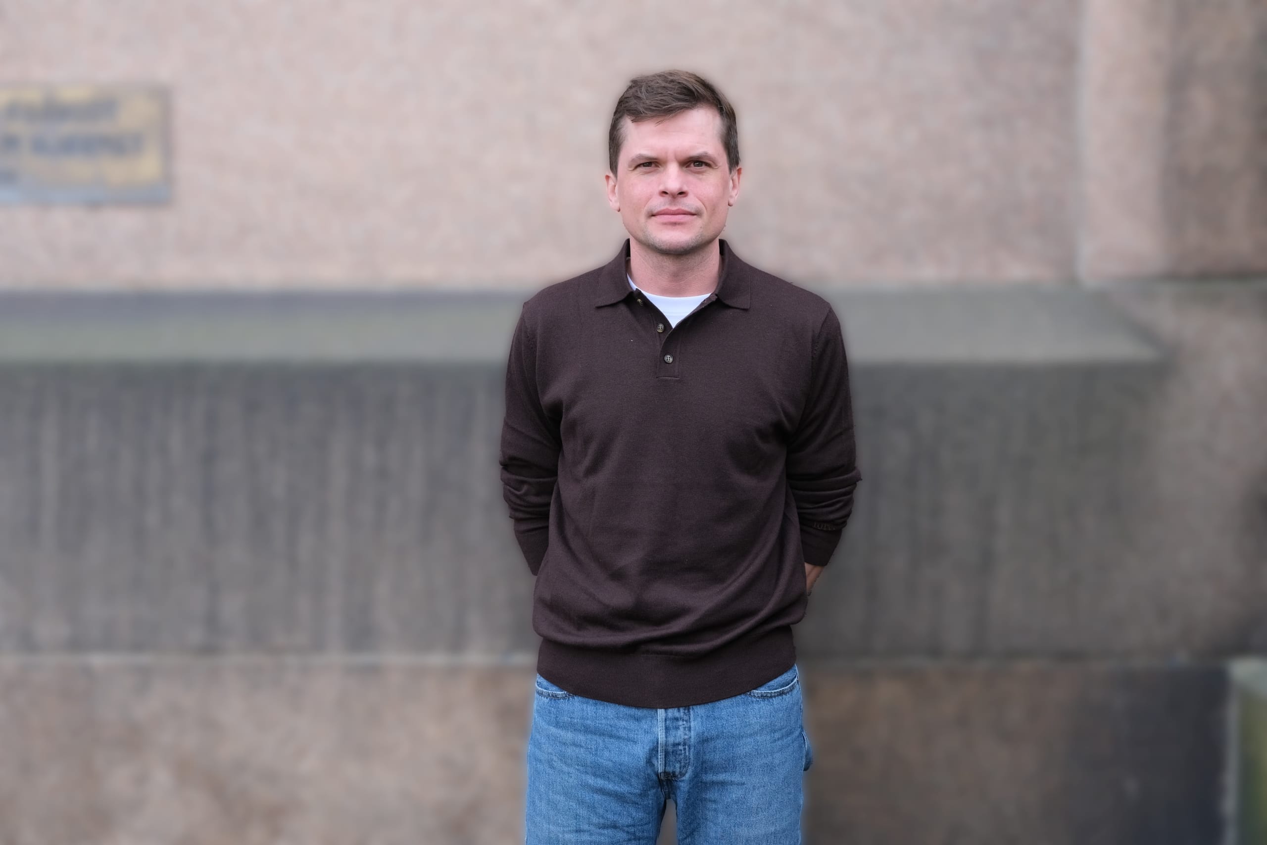 portrett av mann foran murvegg.