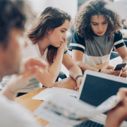 unge mennesker rundt bord, ser på digitale medier. illustrasjonsfoto.