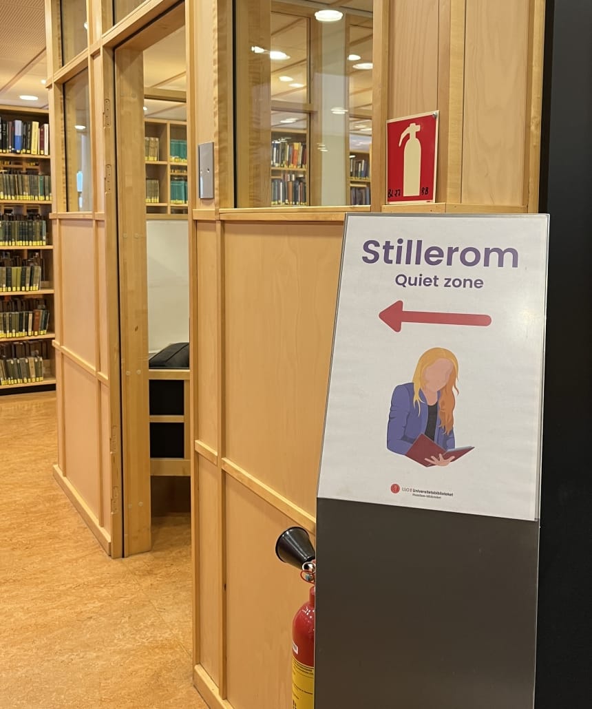 informasjonsplakat med pil som viser retning til stillerom i et bibliotek. foto. 